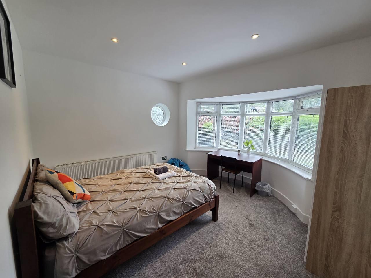 Double bedroom with a bay window, study desk and round feature window — Greenhead Road, Huddersfield